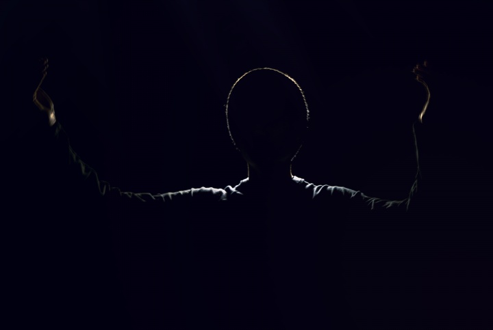 A shadow silhouette of a man with arms in the air.