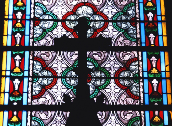 A cross and stained glass window inside a large church.