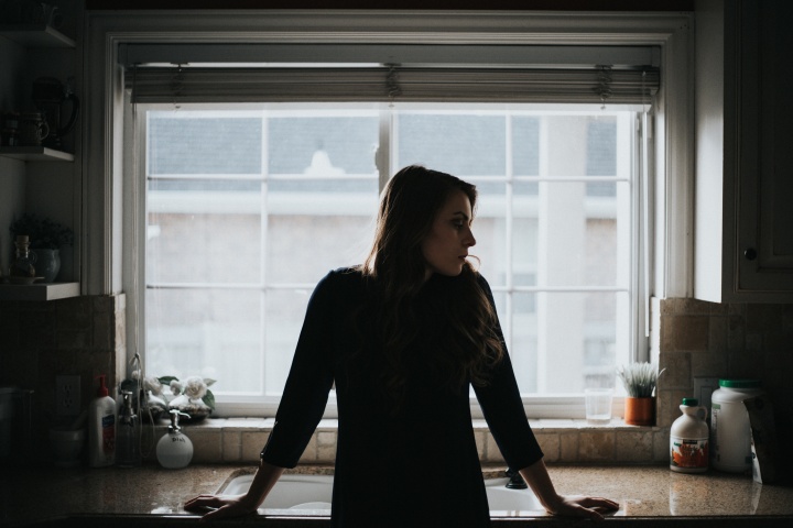 A woman standing by a kitchen sink.