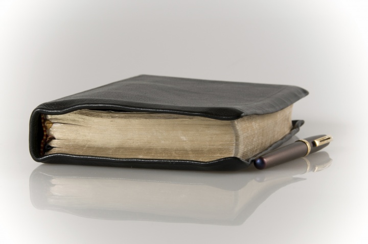 A Bible and pen laying on a table.