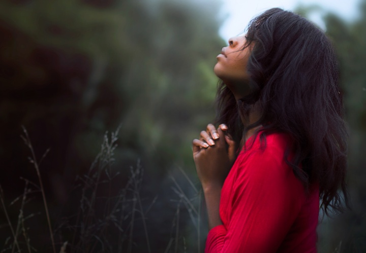 A woman praying while outside.