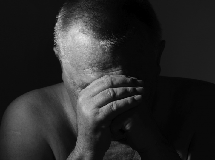 An old man with his head resting on his hands as if he was praying.