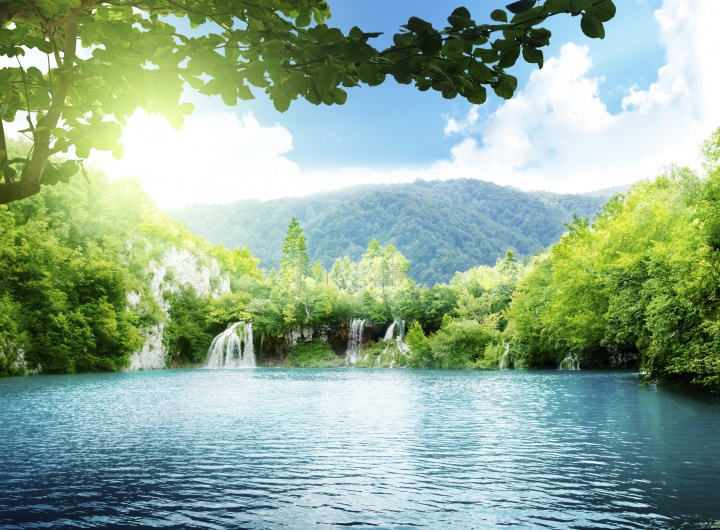 A tropical setting of a lake and waterfalls.