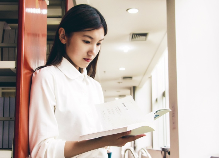 A woman looking at a book in a library.