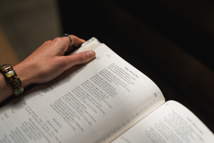 A woman holding a Bible opened to the Psalms. 