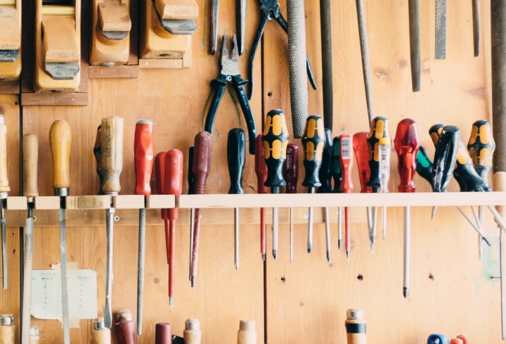 A workbench wall with many types of screwdrivers hanging. 