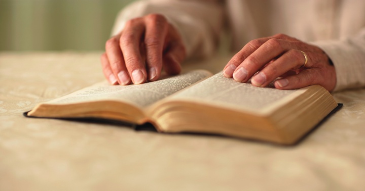 A woman turning the pages of a Bible.