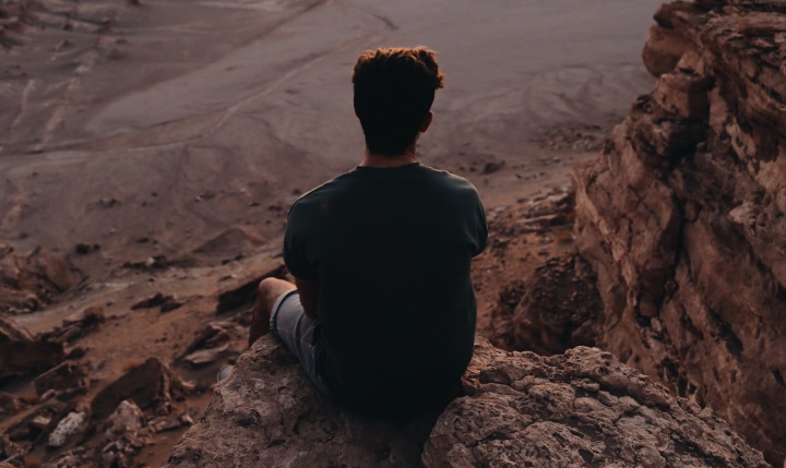 A young man sitting on a rock cliff