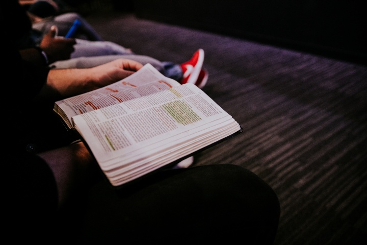 A Bible on the lap of young man.