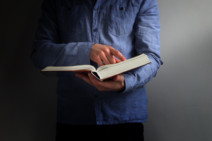 A man wearing a blue shirt holding a Bible.