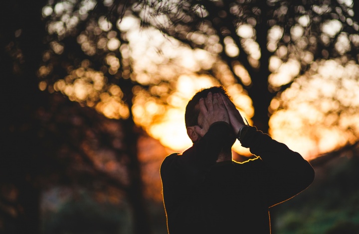 A man with his hands on his face looking up.