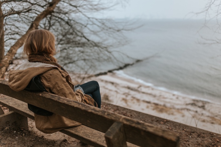 A woman sitting on a bench overlooking water.