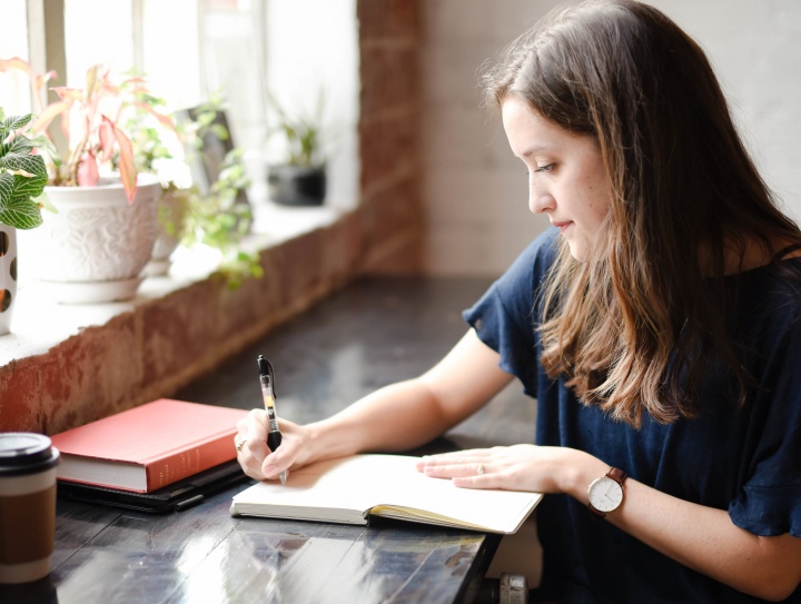 A woman writing in a journal notebook.