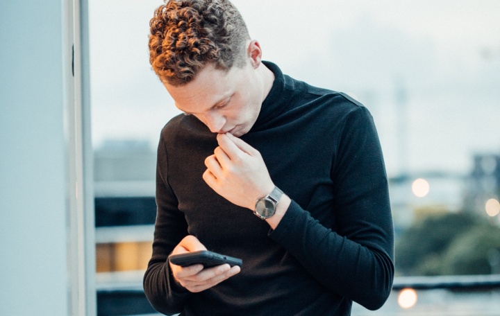 A young man looking down at his smartphone.