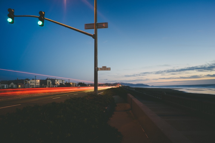 A green light on busy street next to the ocean.