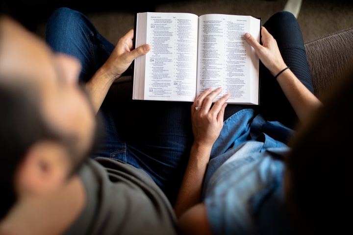 A man and woman holding a Bible together.