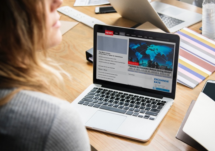 A woman looking at news items on a laptop.