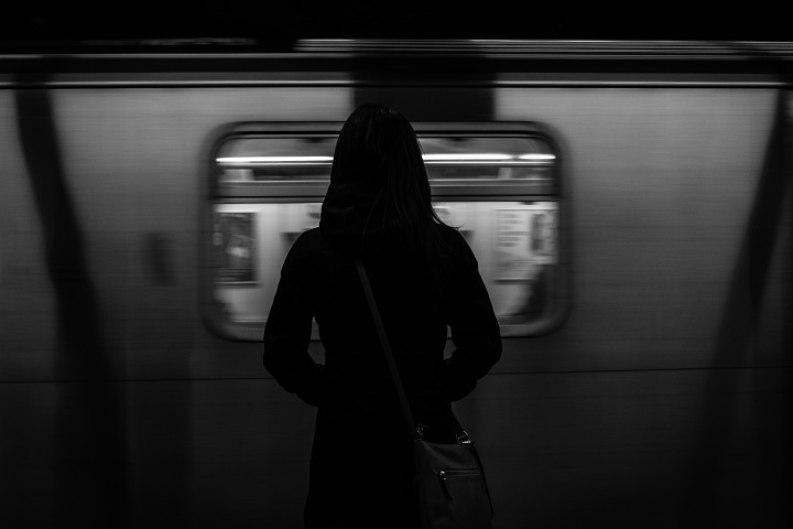 A woman standing by a subway train as it passes by.
