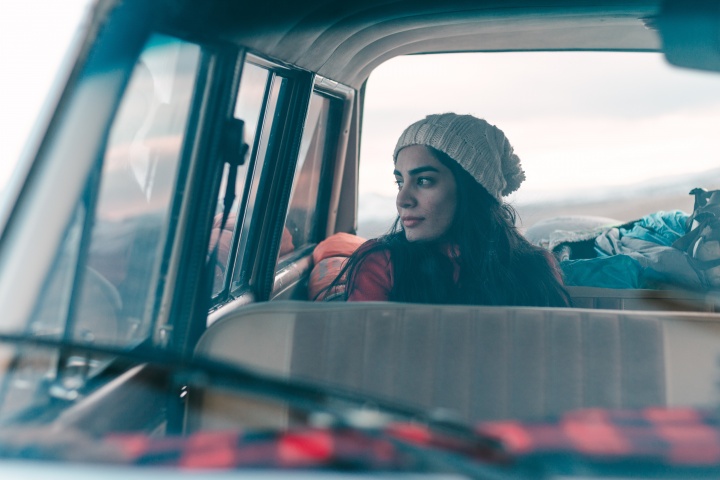 A woman sitting the backseat of a car.