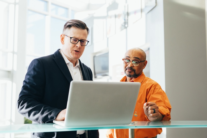 Two men discussing a topic around a laptop.