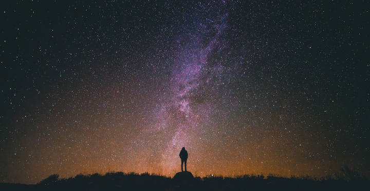 A person standing at night with stars in the background.