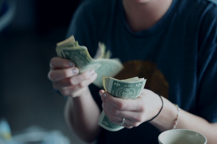 A young woman counting dollar bills.