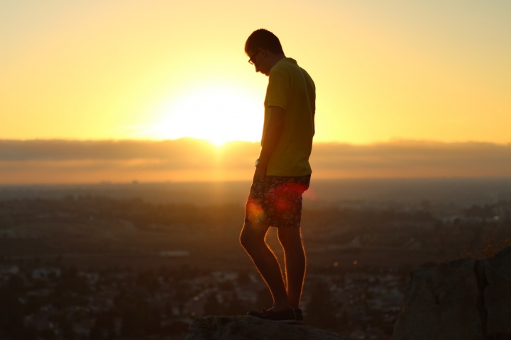 A young man standing on a hill overlooking a village.