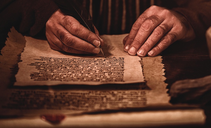 A photo illustration of man writing in a scroll.