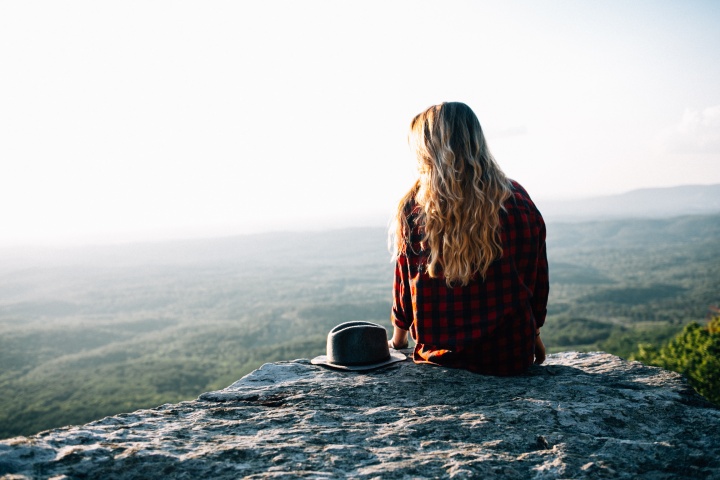 A young woman sitting on a rock.