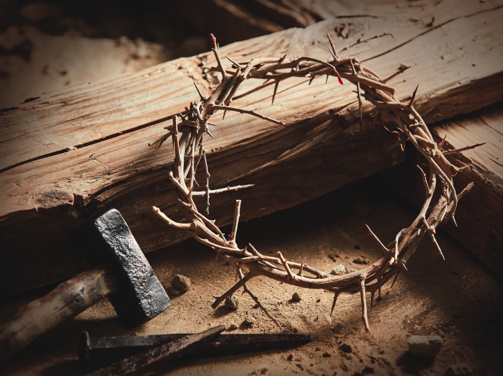 A wooden cross/stake with a crown of thorns, hammer and nails.