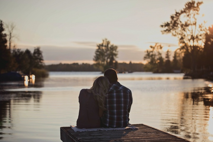 A couple sitting beside each other on a boat dock.