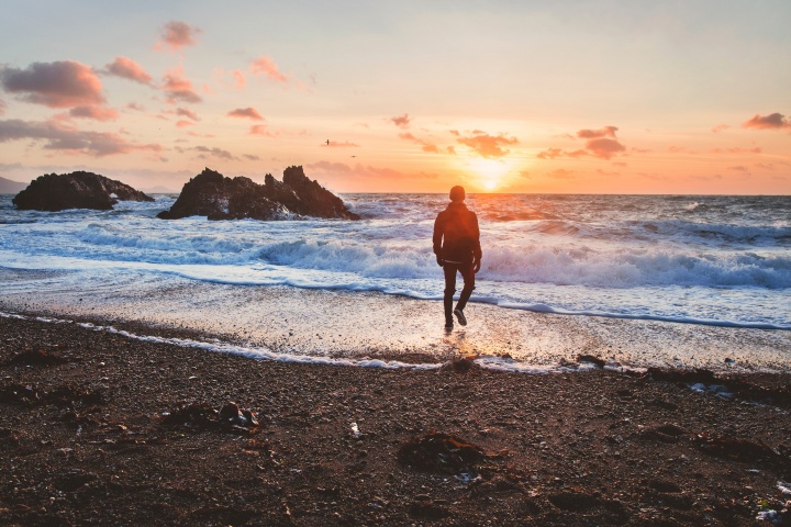 A person walking by water at sunset.