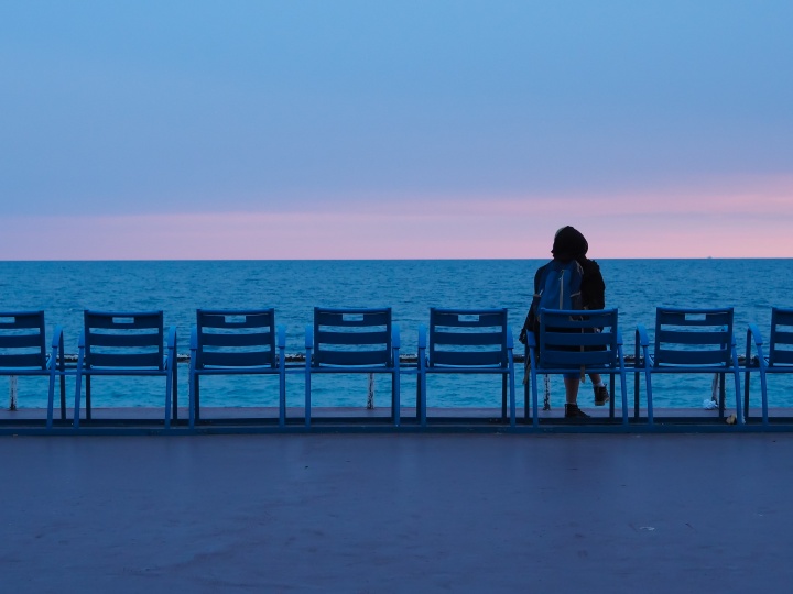 A person sitting watching the water of a sea.