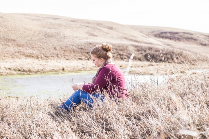 A woman sitting in a field of tall grass.
