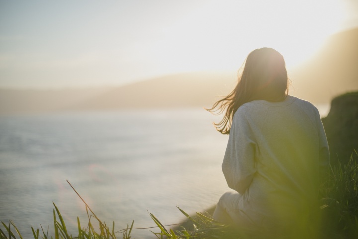 Photo of girl in field sitting quietly.