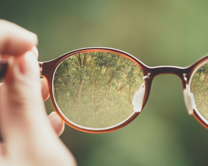 A person holding a pair of glasses.