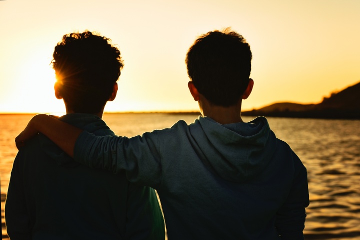 Photo of two boys looking at the sunrise together.