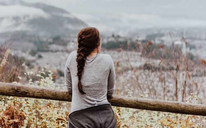 Girl leaning against a fence looking at a valley.