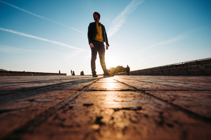 A man walking on a cobblestone sidewalk.