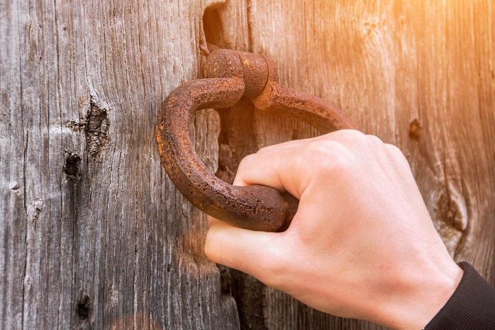 A person holding onto a door knocker.