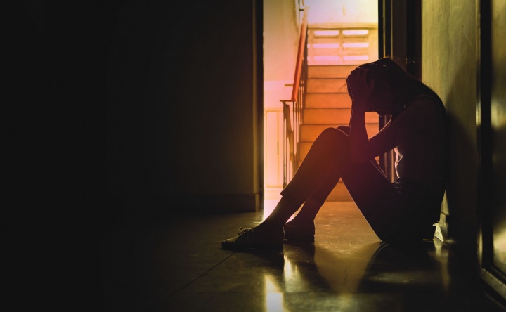 A sad woman sitting on the floor in a hallway.