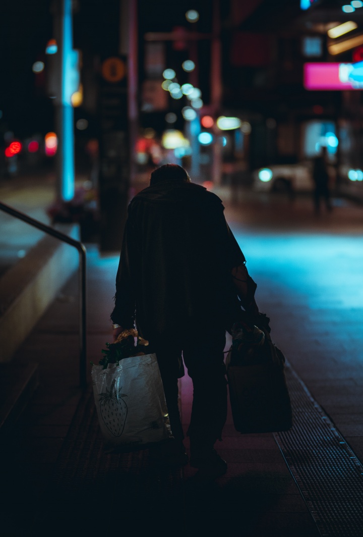 Homeless man walking down street at night under street lights