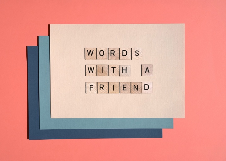 Layered cardstock paper in multiple colors with Scrabble tiles spelling the article title, words with a friend