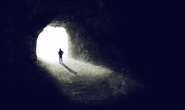 A man in a dark cave looking out from the entrance