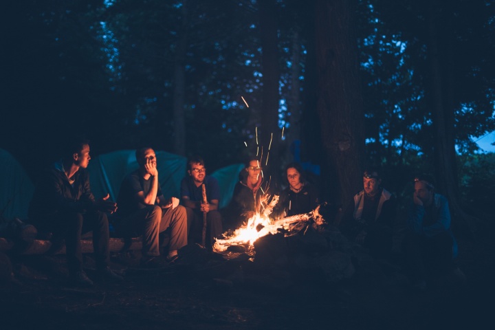 A group of young people around a campfire at night.