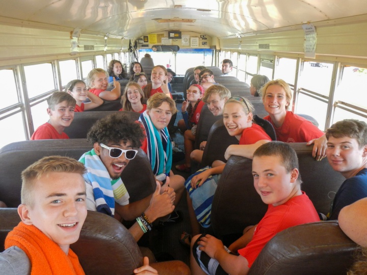 a group of teenagers sitting on a bus and turning to face the camera