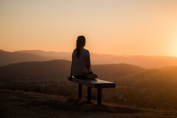 A silhouette of a woman sitting on a bench.