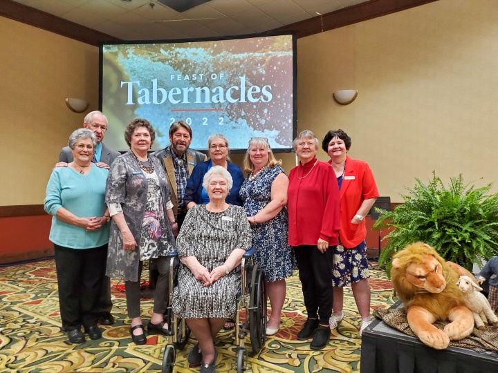 a group of brethren gathered in front of the Feast of Tabernacles banner