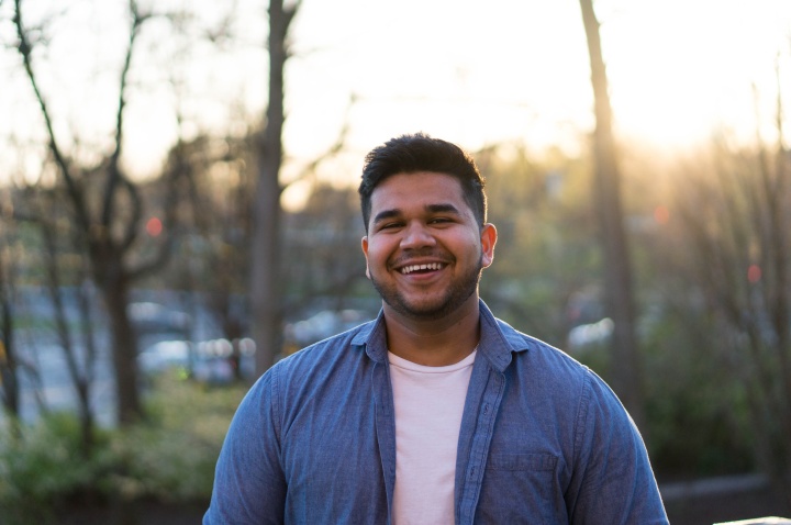 a man standing outdoors with woods in the background