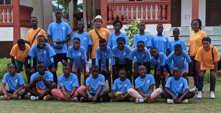 a group of children, teenagers, and camp staff gathered outdoors in matching camp shirts